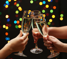woman hand with glasses of champagne, on garland background.