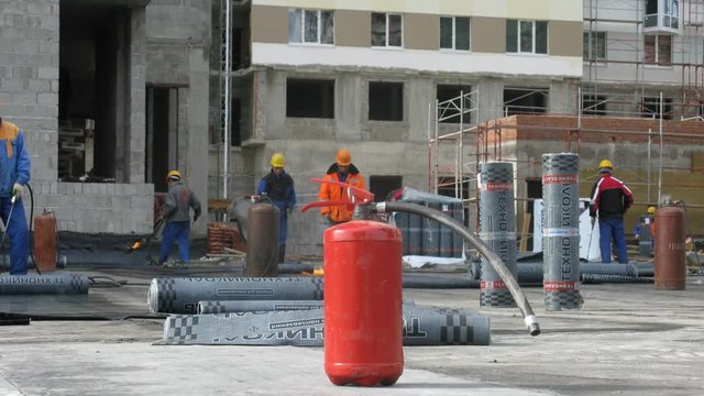 Extinguisher stands in front of workers which work with fire on