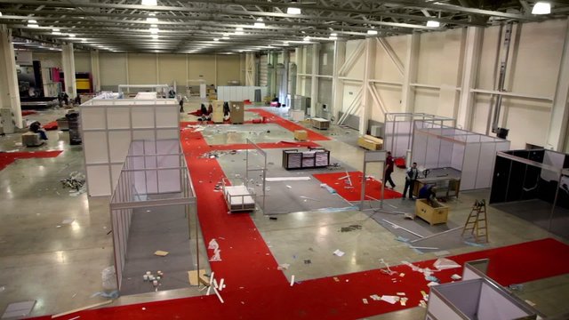 Several workers remove stands in exhibition hangar