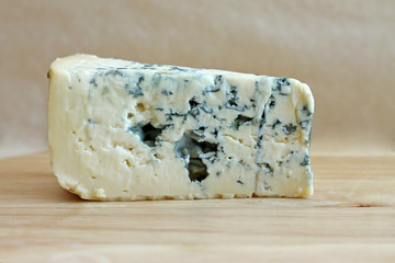 Slice of blue cheese on wooden background, close-up