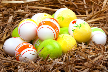 bemalte bunte Eier für Ostern versteckt im Nest aus Stroh