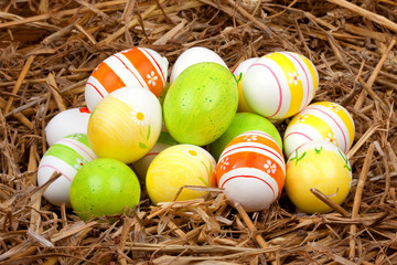 Naklejka na ściany i meble bemalte bunte Eier für Ostern versteckt im Nest aus Stroh
