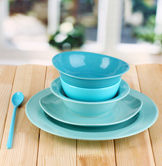 Blue tableware on wooden table on window background