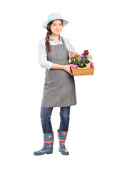 Full length portrait of a female gardener holding flower plants