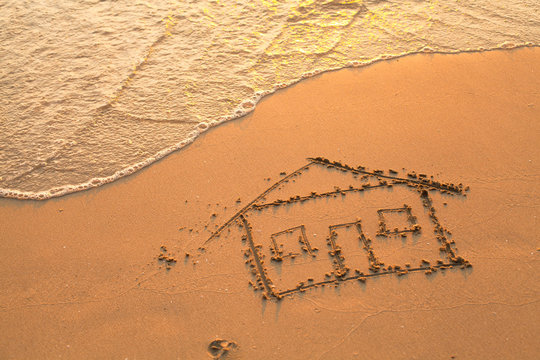 Conceptual photo: a house painted on beach sand