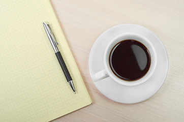 Coffee cup with note book on table