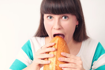 Pretty girl holding and biting loaf of bread