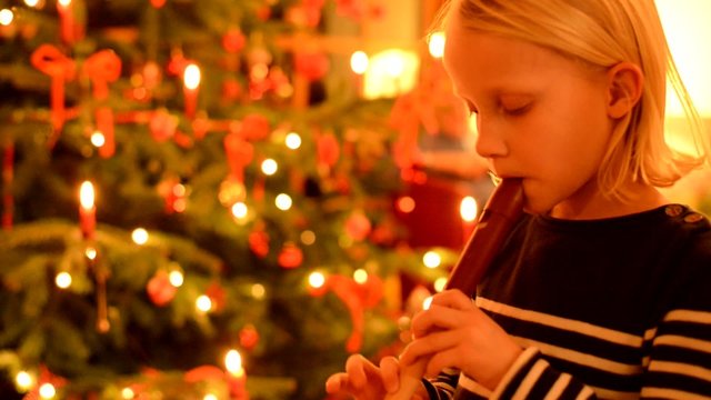 Kleines M&auml;dchen spielt Blockfl&ouml;te vor Christbaum