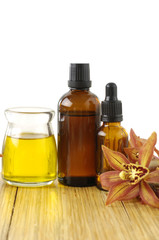 bottle of aromatherapy oil and orchid on wooden board