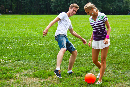 man and woman playing football in the park
