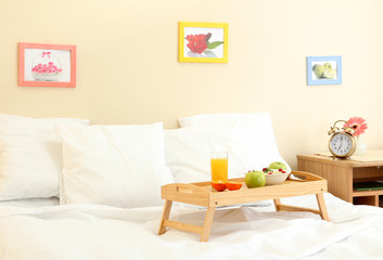 wooden tray with light breakfast on bed