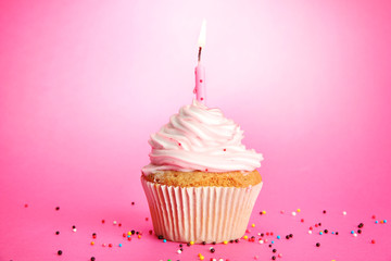 tasty birthday cupcake with candle, on pink background