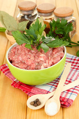 Bowl of raw ground meat with spices on wooden table