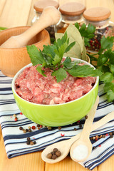 Bowl of raw ground meat with spices on wooden table