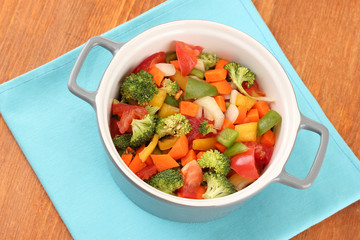 Vegetable stew in gray pot on color napkin on wooden background