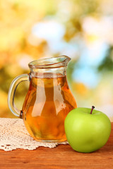 Full jug of apple juice and apple