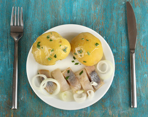 Dish of herring on plate on blue wooden table close-up