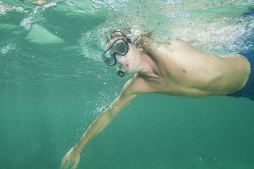 man swims in the ocean with mask