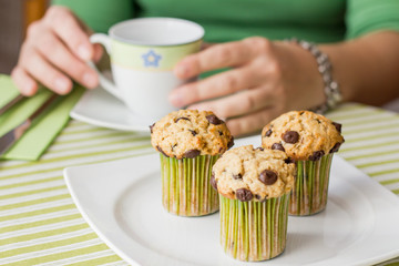 Nice girl with a cup and chocolate chip muffin at breakfast