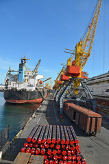 Pipe stack, ship ans train under crane bridge