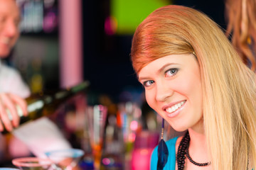 Young woman in club or bar drinking champagne