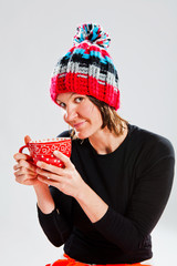 Smiling woman in knitted hat holding cup