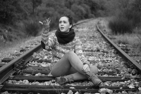 Mujer joven juega lanzando una piedra en las vias de tren