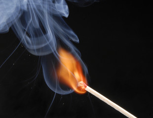 Encendiendo un cerillo,fósforo encendido en fondo negro.