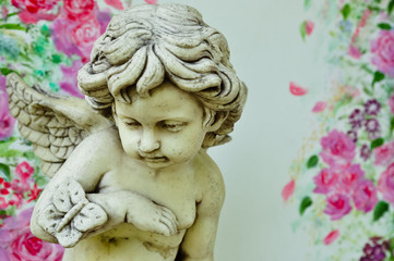 Obraz premium Vintage cupid sculpture with floral background