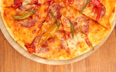 Tasty pepperoni pizza on wooden board on wooden background