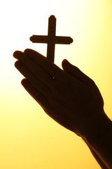 man hands with crucifix, on yellow background.