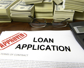 Approved loan application form and dollar bills