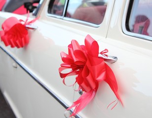 a vintage white wedding car with red ribbon