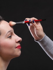 Obraz premium beautiful young brunette woman applying powder with a brush