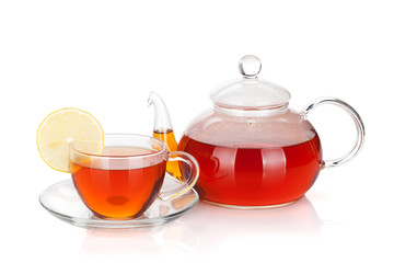 Glass teapot and cup of black tea with lemon slice