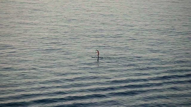 Man with oar floating on the sea
