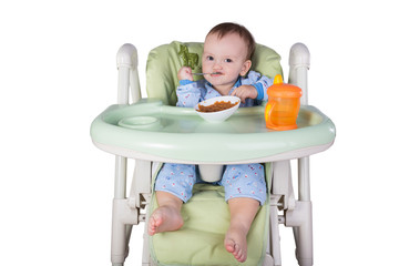 child is eating sitting at table, isolated over white