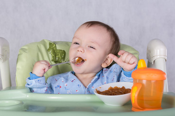 child is eating sitting at table, isolated over white