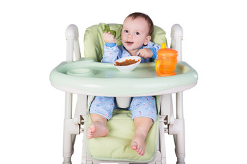 child is eating sitting at table, isolated over white