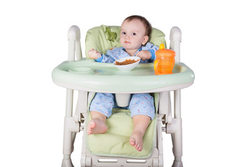 child is eating sitting at table, isolated over white