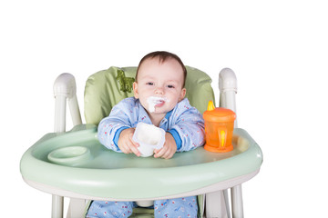 child is eating sitting at table, isolated over white