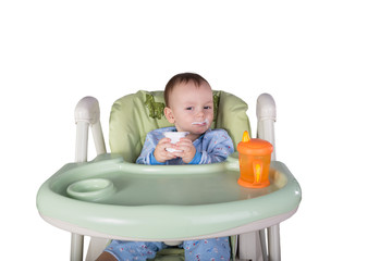 child is eating sitting at table, isolated over white