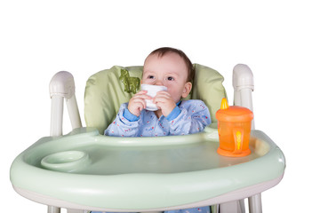 child is eating sitting at table, isolated over white