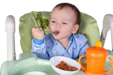 child is eating sitting at table, isolated over white