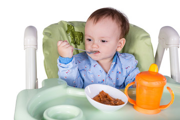 child is eating sitting at table, isolated over white