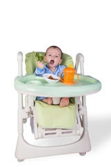 child is eating sitting at table, isolated over white