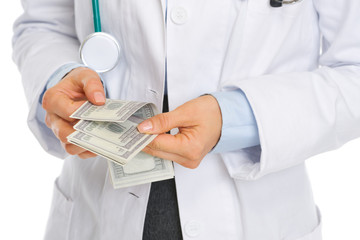 Closeup on medical doctor counting dollars