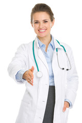 Fototapeta premium Smiling medical doctor woman stretching hand for handshake