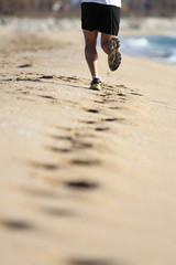 Man legs running on the sand of a beach