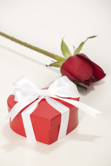 Heart-shaped Valentines Day gift box with rose over a white 